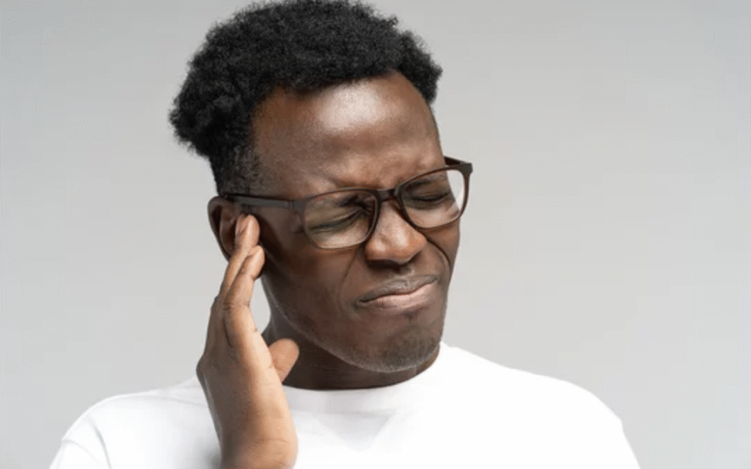 Man holding ear in pain, possibly experiencing muscle-based tinnitus