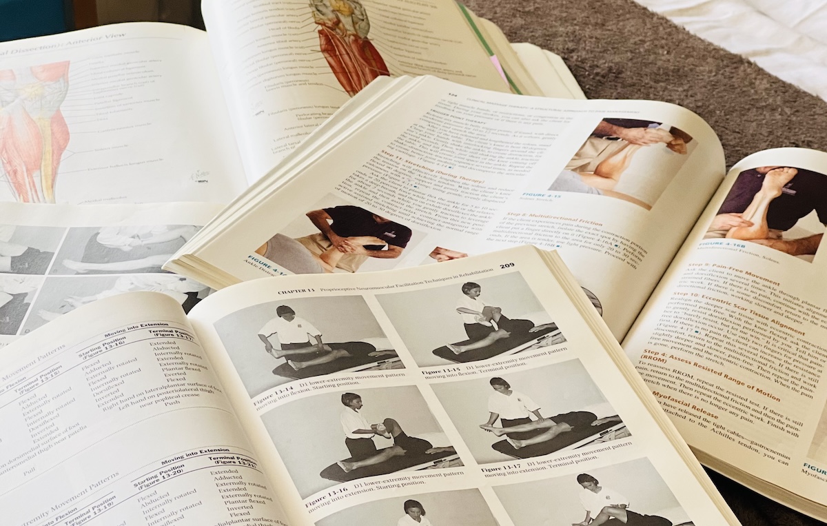 Open anatomy and manual therapy textbooks with clinical images and diagrams, representing evidence-based assessment methods in healthcare.